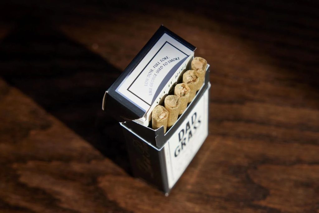 george-harrison-dad-grass-five-pack-12109897 Close-up of a box of hemp CBD pre-rolls on a wooden background.